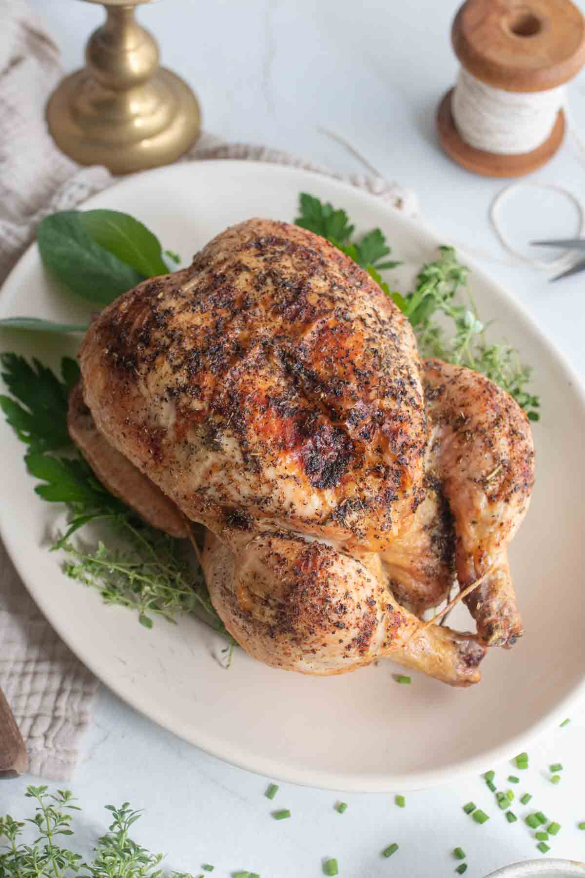 A roasted whole chicken on a white platter.