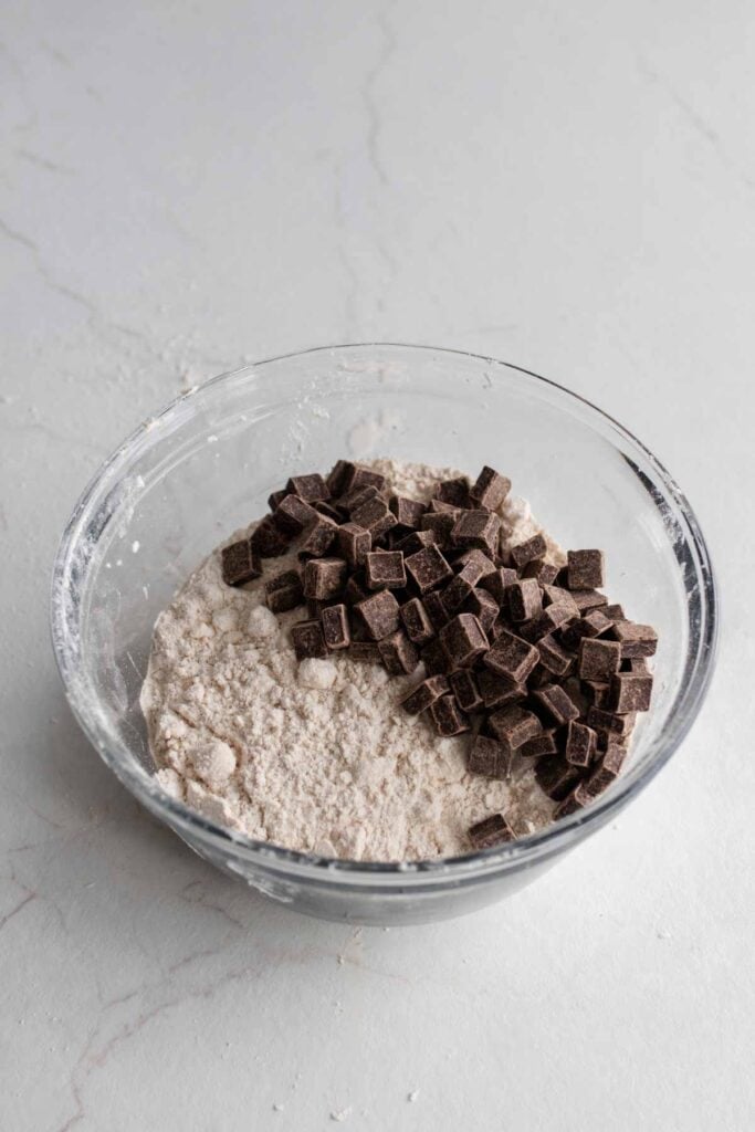 Chocolate chunks in a bowl with dry ingredients.