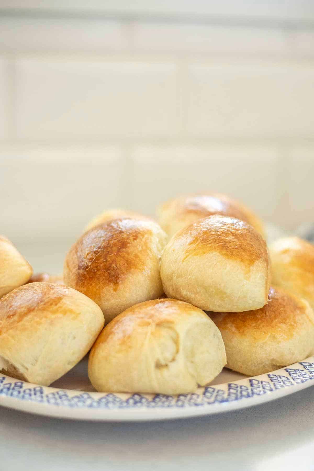 Sourdough brioche rolls stacked on a blue and white plate.