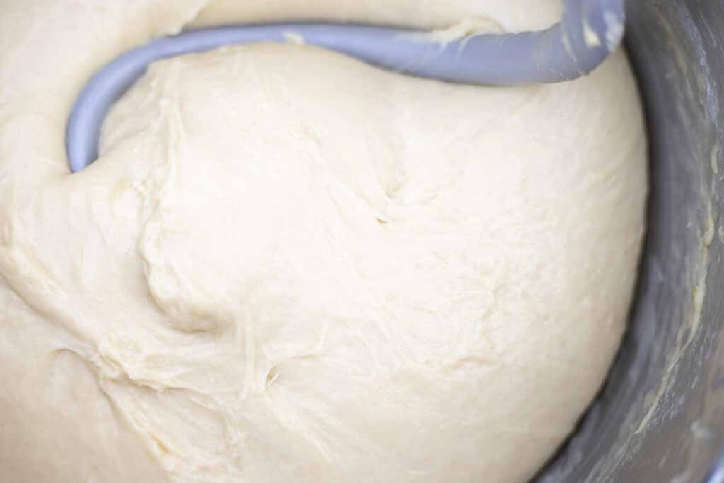 Sourdough brioche dough in a stand mixer with a dough hook attachment.