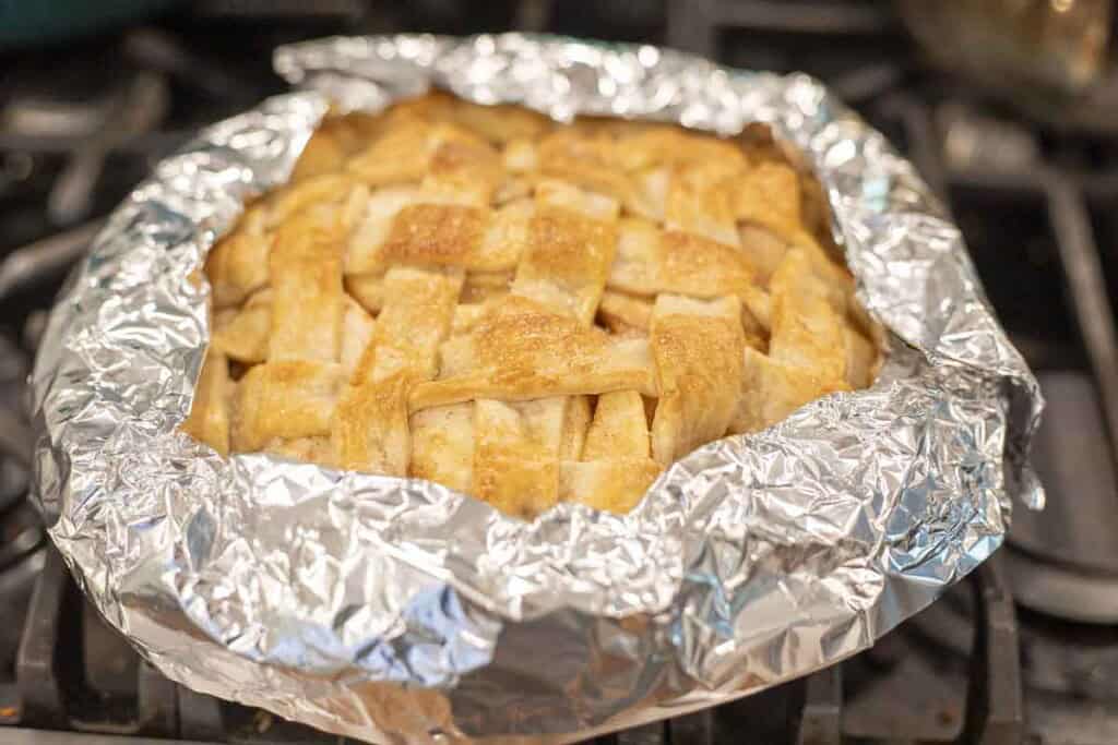 a apple pie with tinfoil wrapped around the edges.