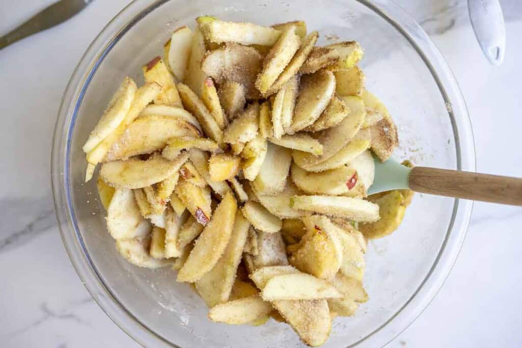 Sliced apples, flour, sugar and cinnamon mixed in a bowl.