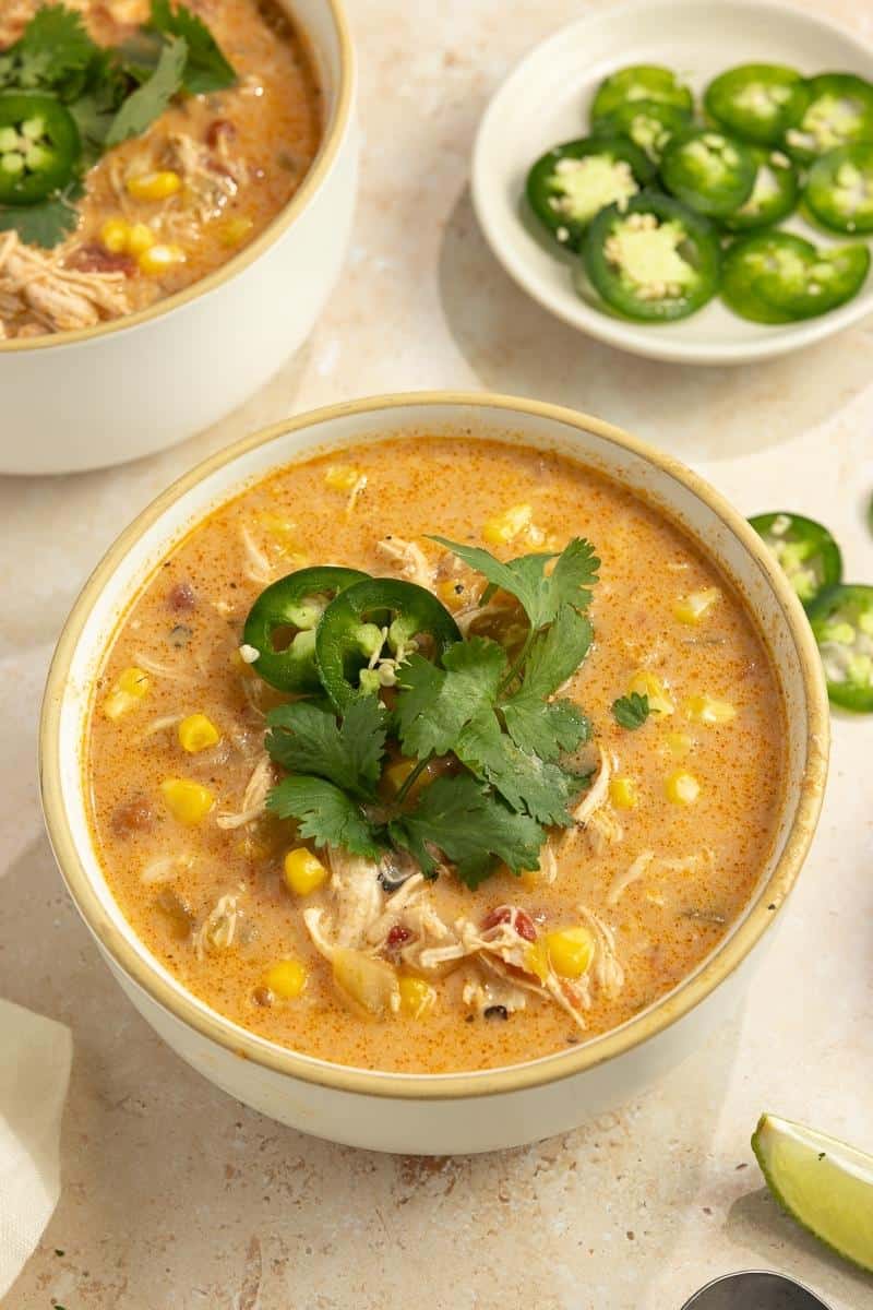 A bowl of white chicken chili topped with jalapeno slices and cilantro.