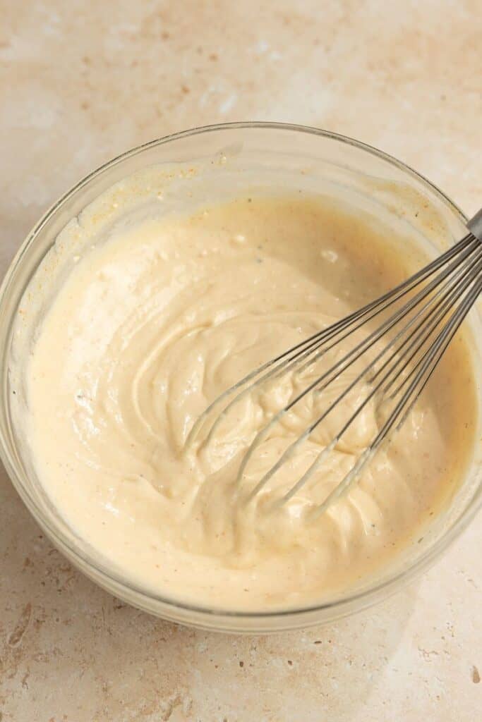 A small bowl with cream cheese and broth mixed together with a whisk.