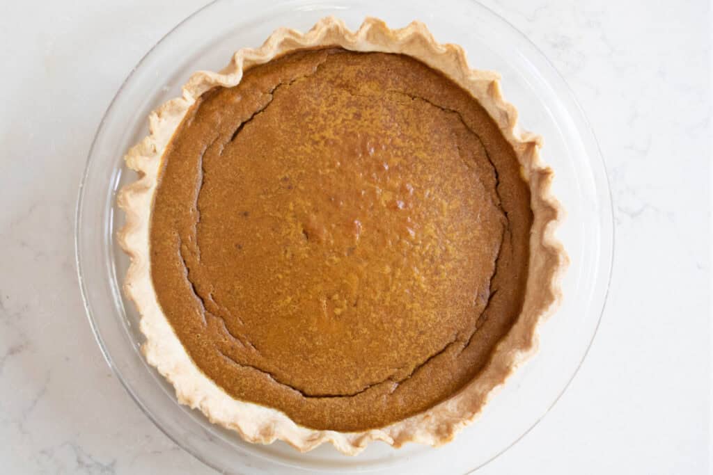 A pumpkin pie on a white countertop.