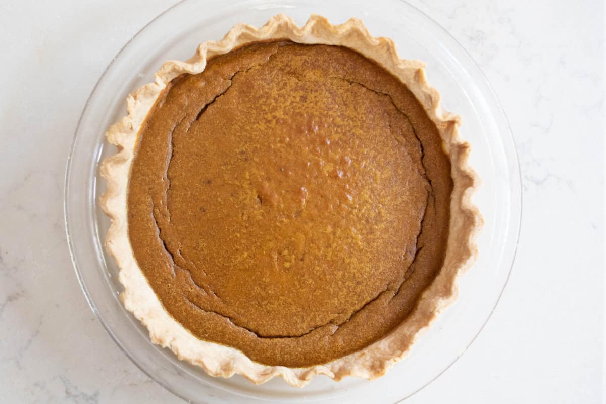 A pumpkin pie on a white countertop. 