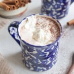 Two mugs filled with hot chocolate and topped with whipped cream.