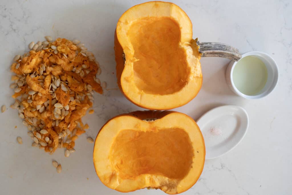 A sugar pumpkin cut in half with the seeds scooped out.