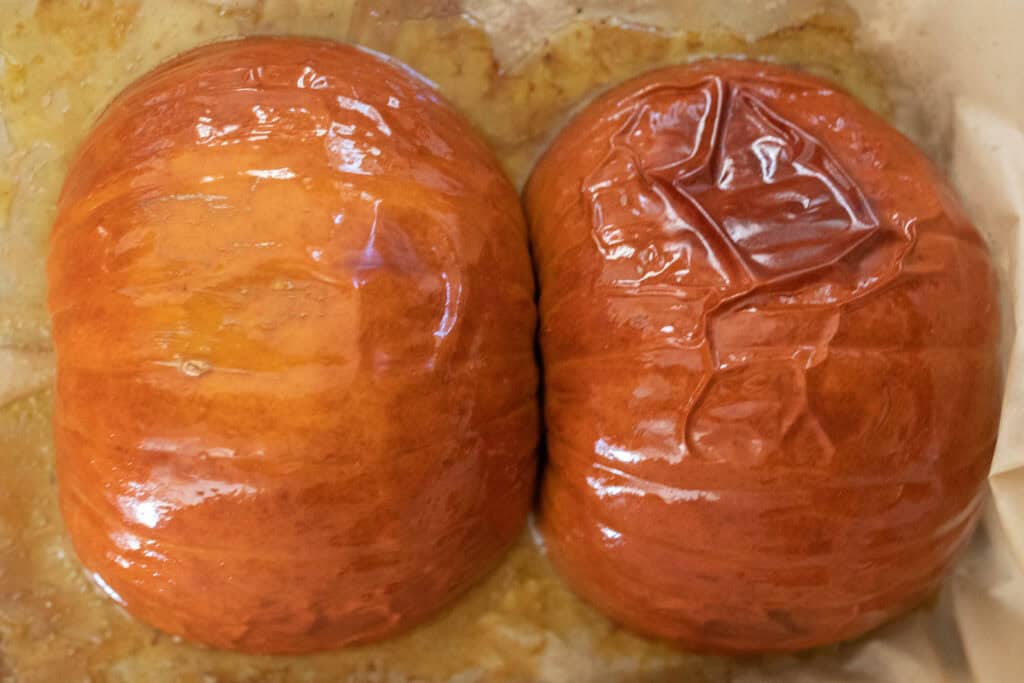 Two halves of a pie pumpkin on a baking sheet after being roasted.