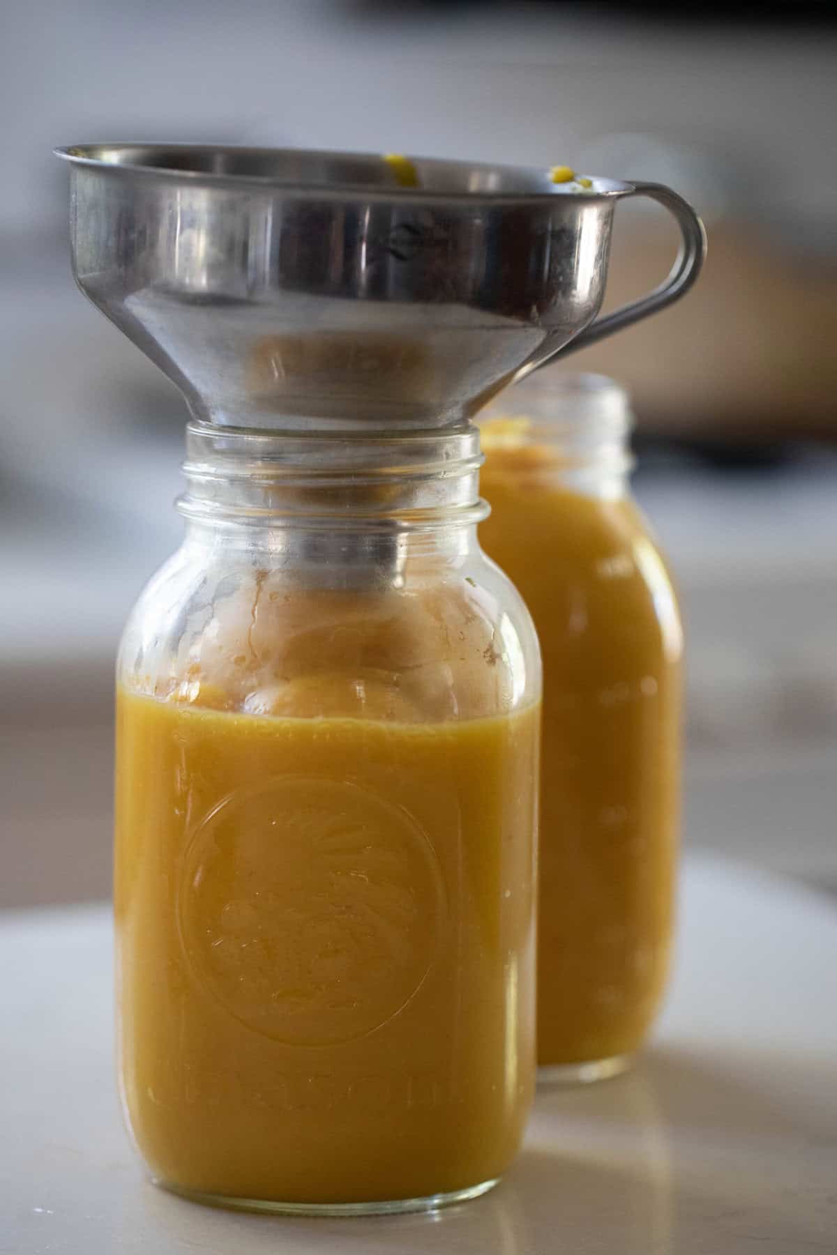 Pumpkin puree funneled into a glass mason jar.