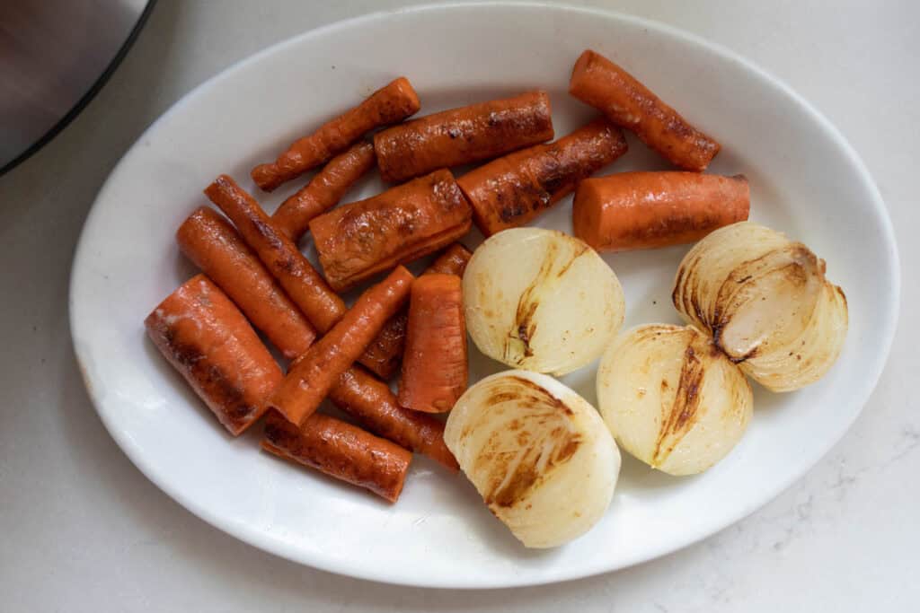 Carrots and potatoes that have been seared on a white plate.