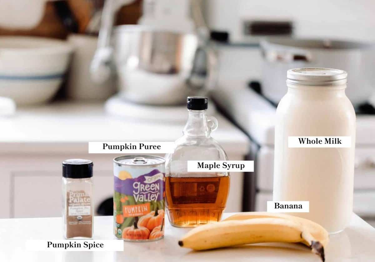 pumpkin smoothie ingredients spread out on a white countertop.