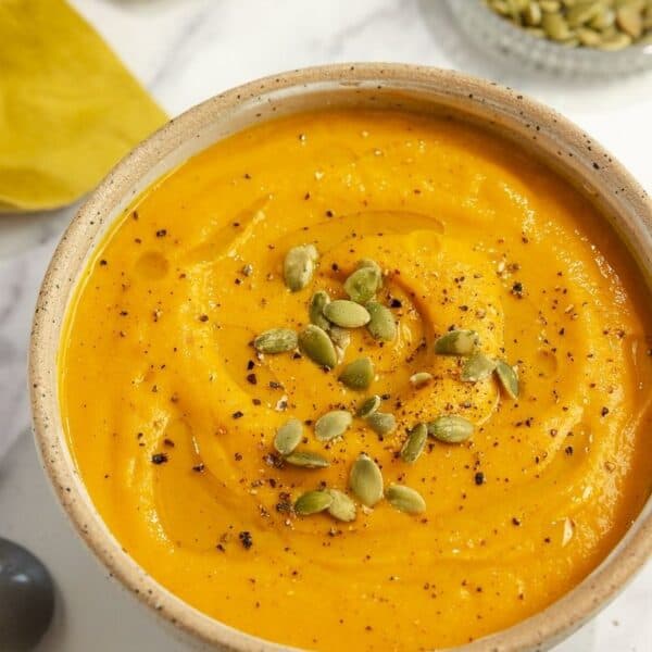 A bowl of roasted pumpkin soup garnished with pumpkin seeds.