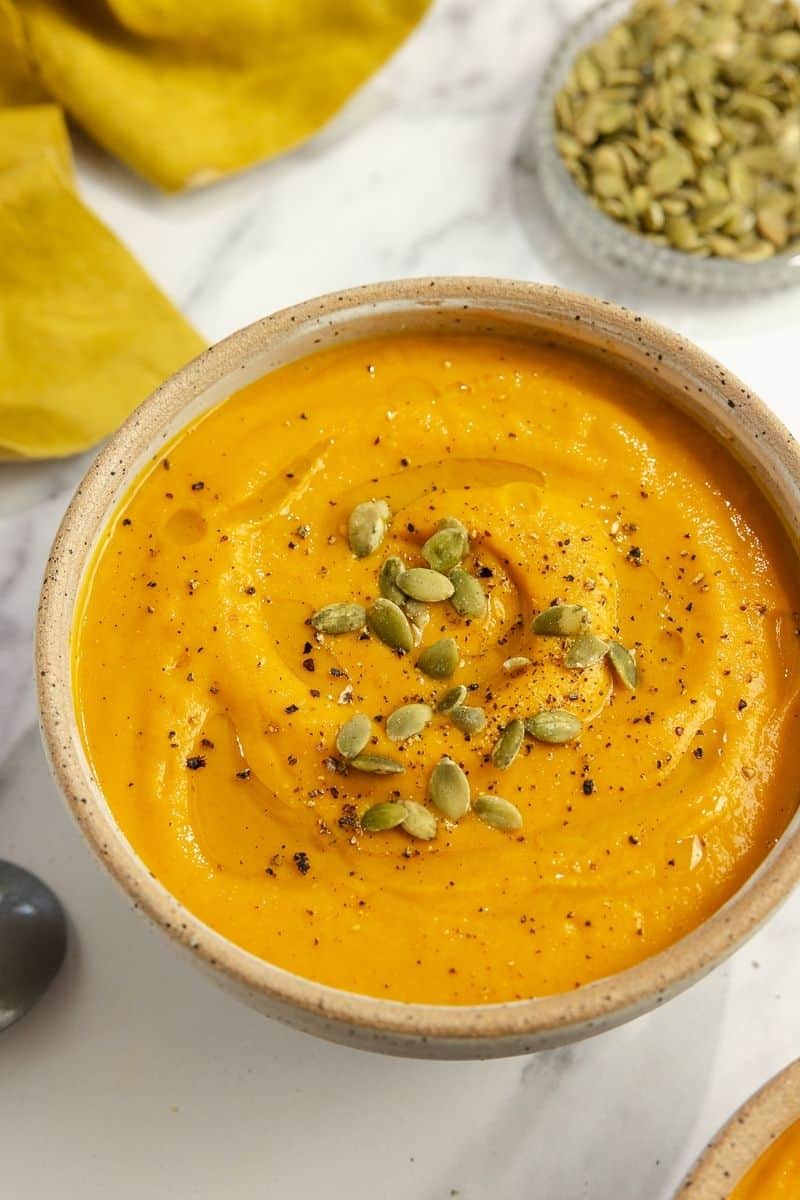 A bowl of roasted pumpkin soup garnished with pumpkin seeds.