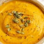 A bowl of roasted pumpkin soup garnished with pumpkin seeds.