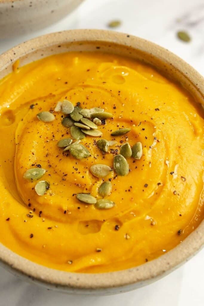 A bowl of roasted pumpkin soup garnished with pumpkin seeds.