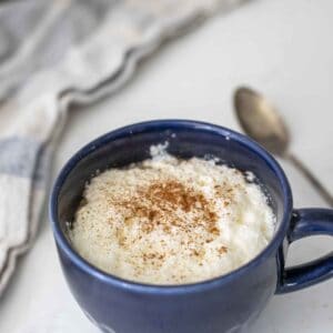 Close up of a rooibos tea latte topped with frothed milk and cinnamon in a blue mug.