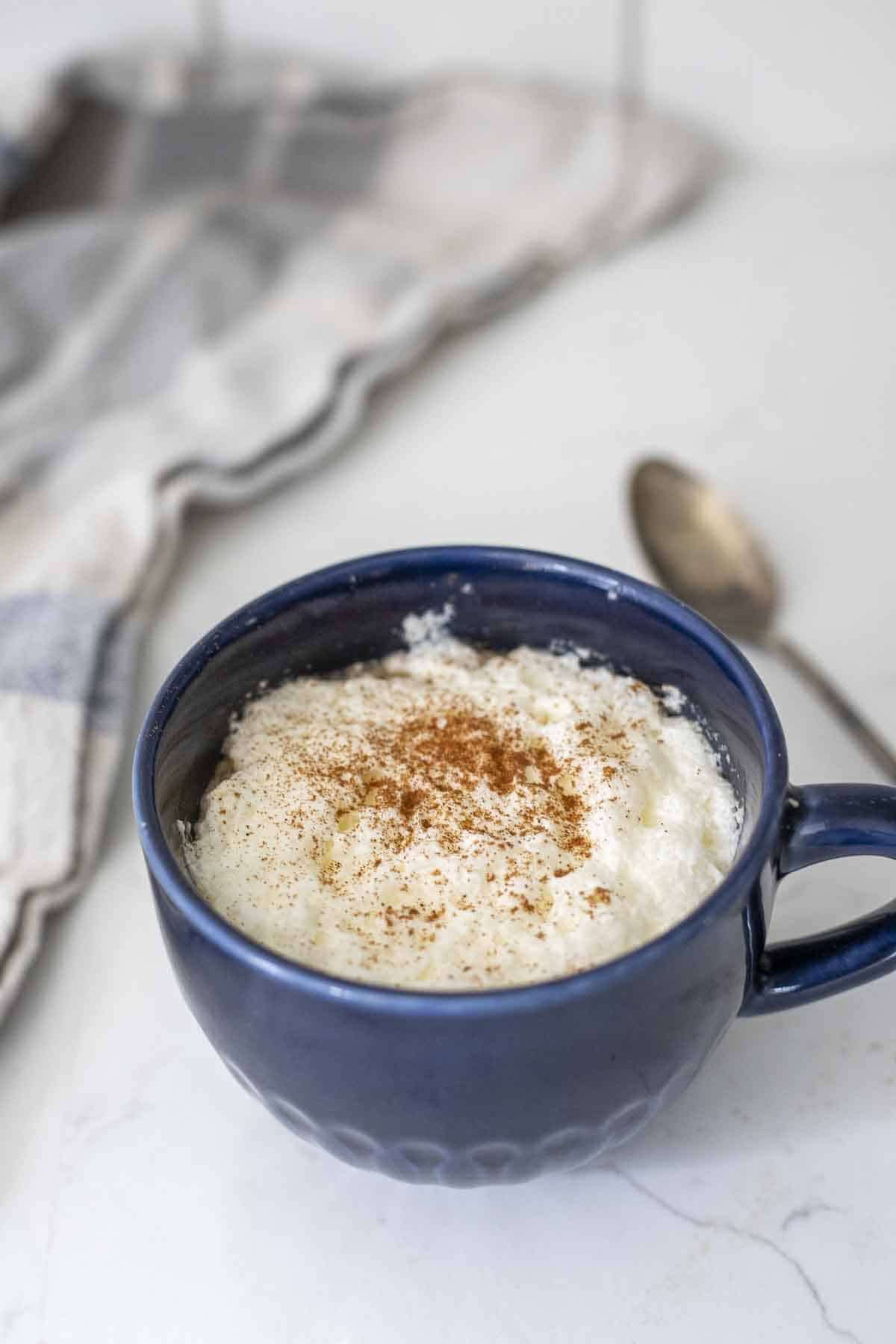 Close up of a rooibos tea latte topped with frothed milk and cinnamon in a blue mug.