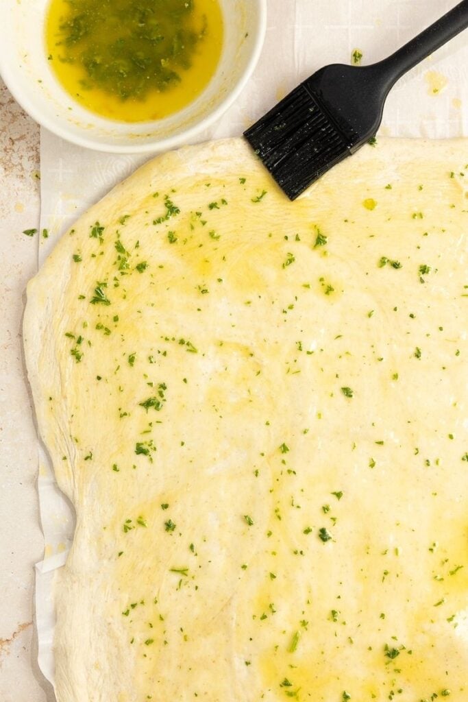 bread dough rolled out and spread with butter and parsley