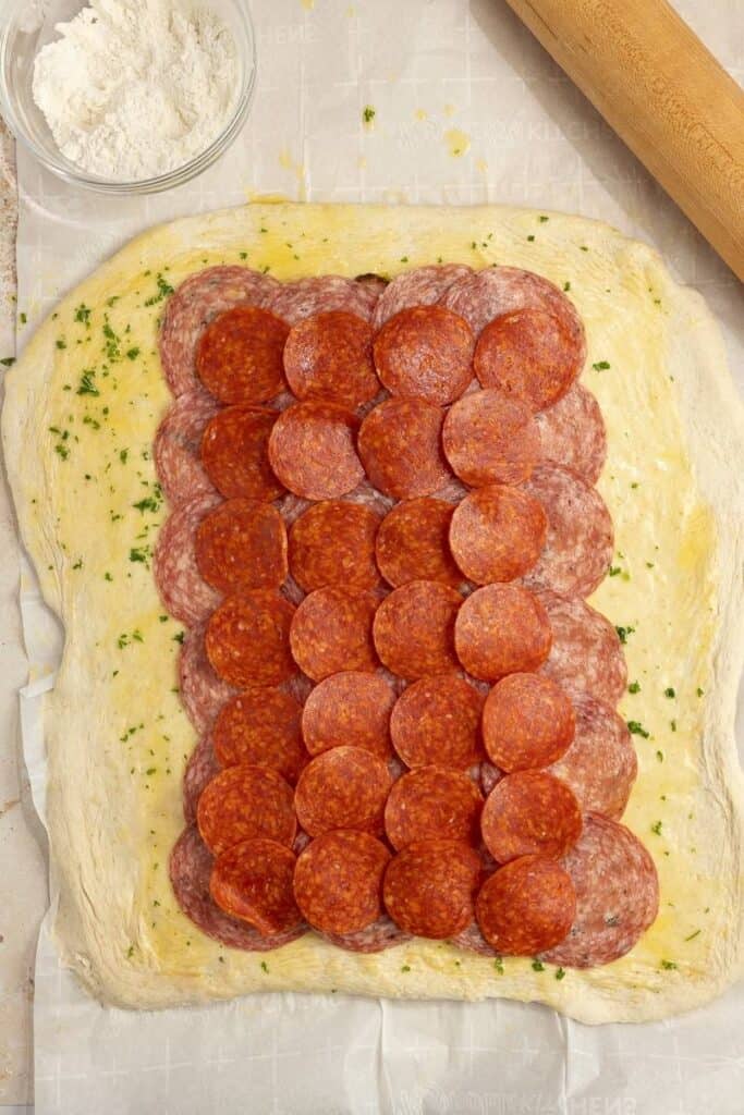 sourdough bread rolled out and topped with butter, parsley, and a variety of cheese and deli meats.