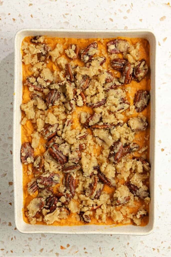 A sweet potato casserole topped with a pecan crumble ready to be baked.