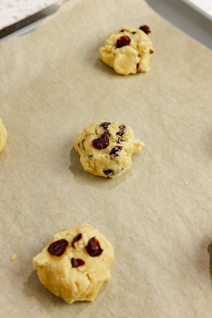 Cookie dough balls scooped onto a parchment lined baking sheet.