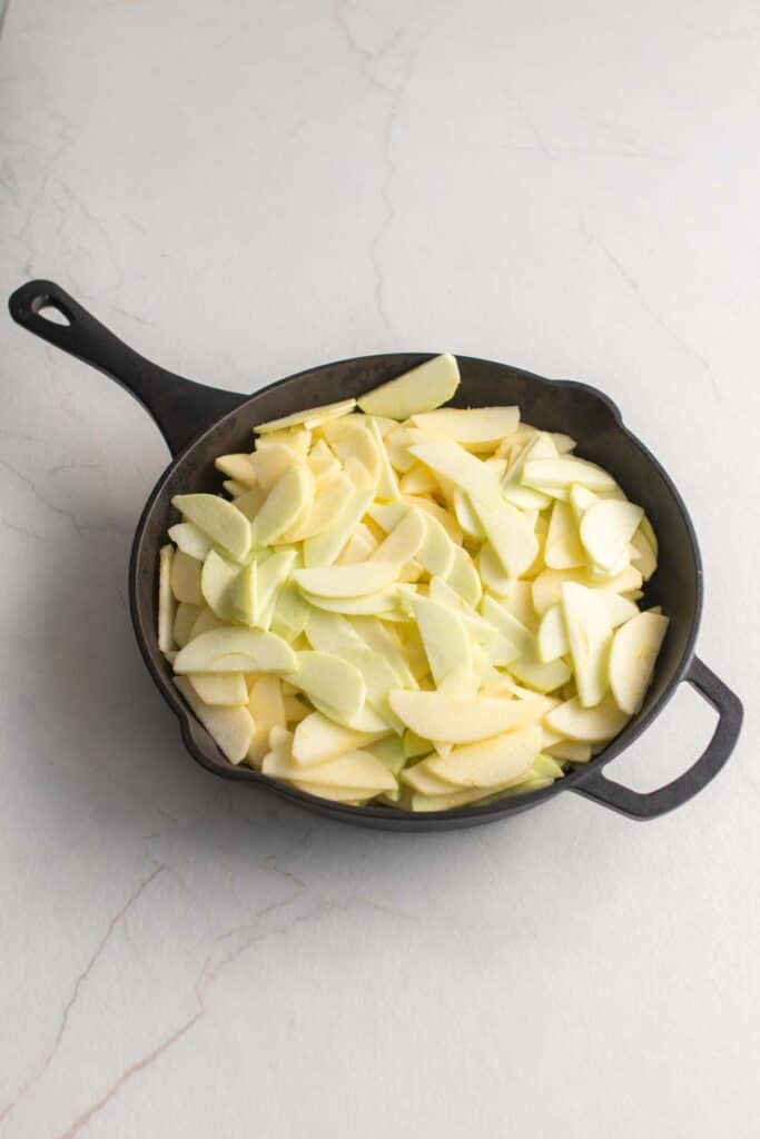 Peeled and sliced apples in a cast iron skillet.