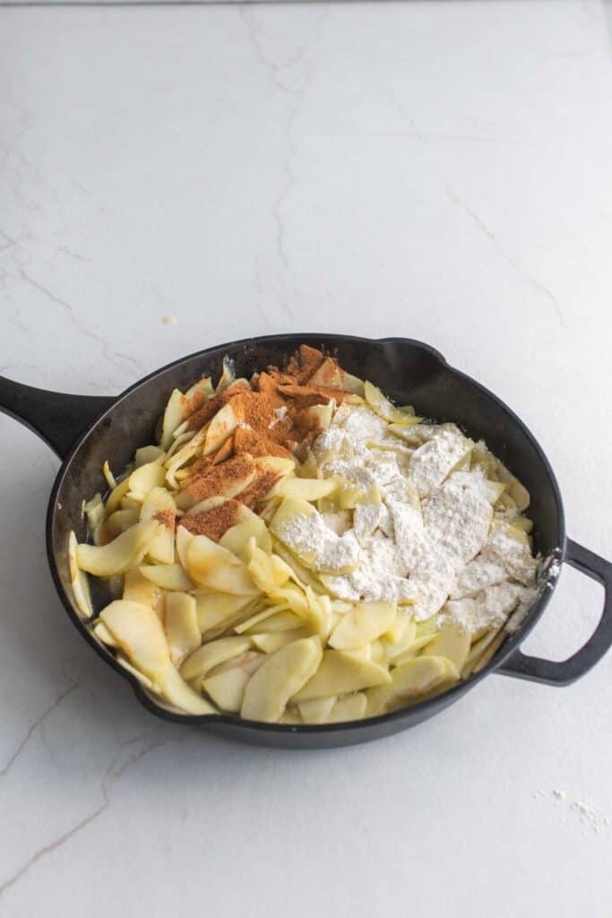 Seasonings and flour added to the sliced apples in the cast iron skillet.