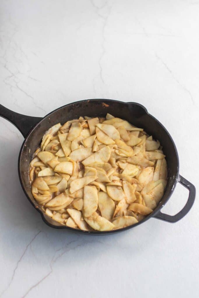 Cooked apple slices in cast iron skillet.