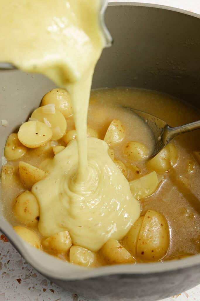 Adding in pureed soup into the remaining potato soup. 