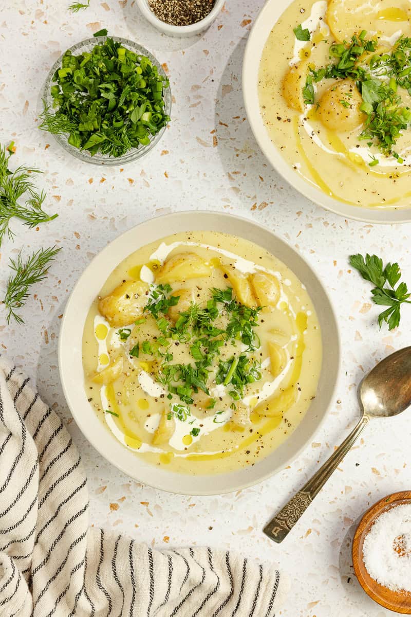 two bowls of potato soup topped with cream and fresh parsley. 