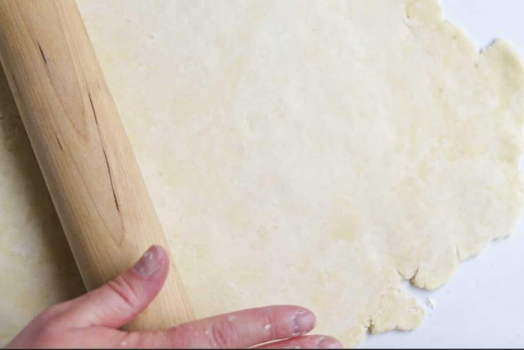 Pie dough rolled out in a circle with a rolling pin. 