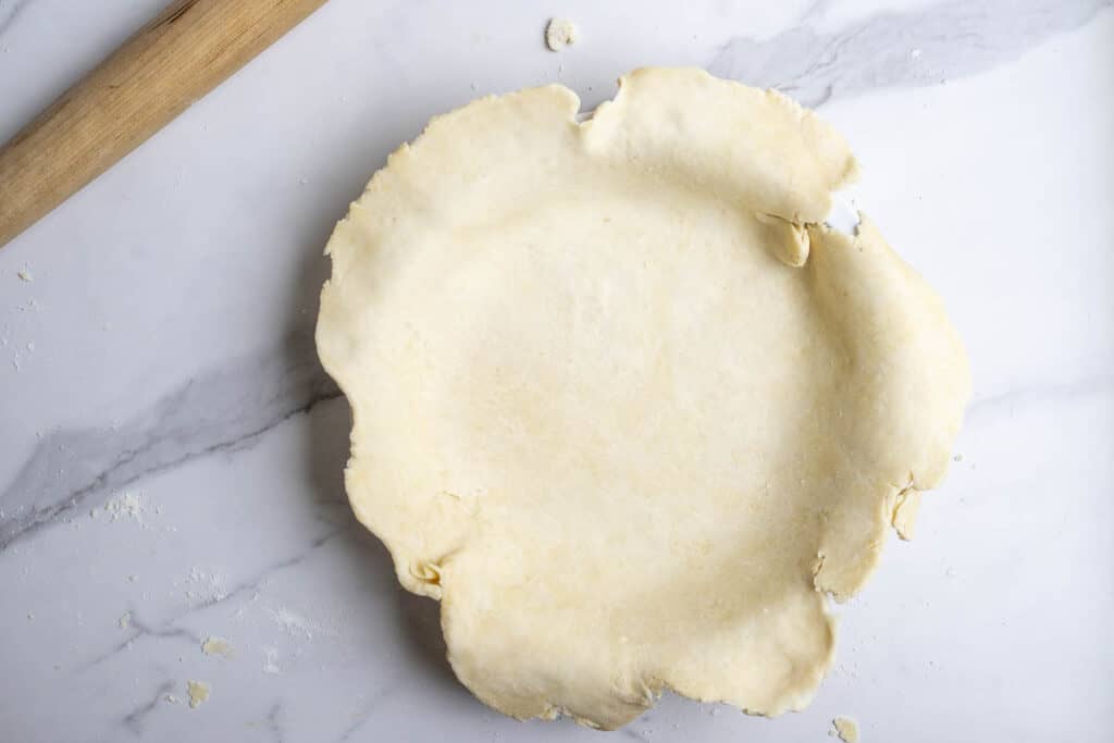 A pie crust in a pie pan before baking.