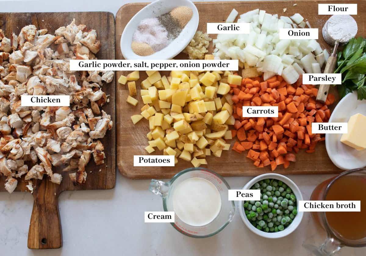 chopped vegetables, shredded chicken, butter, cream and other ingredients on cutting boards.