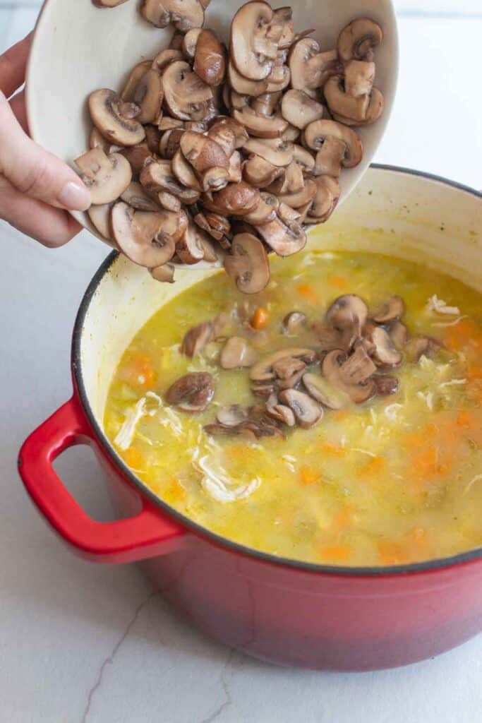 Mushrooms added back into a dutch oven full of soup. 