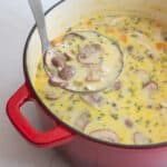 A large ladle scooping out soup from a large dutch oven.