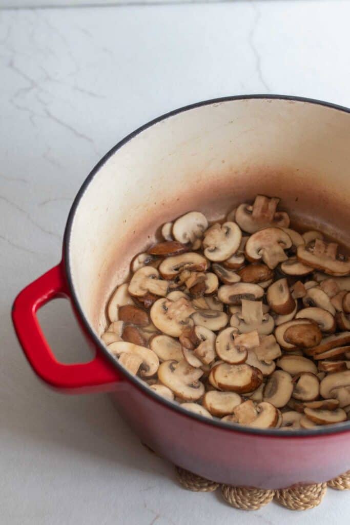 Sliced mushrooms in a large dutch oven. 