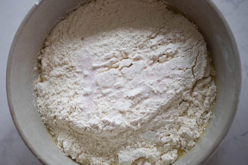 Adding flour to liquid ingredients in a bowl.