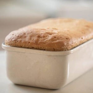 loaf of einkorn sandwich bread in a loaf pan on a countertop.