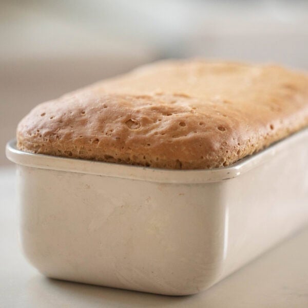 loaf of einkorn sandwich bread in a loaf pan on a countertop.