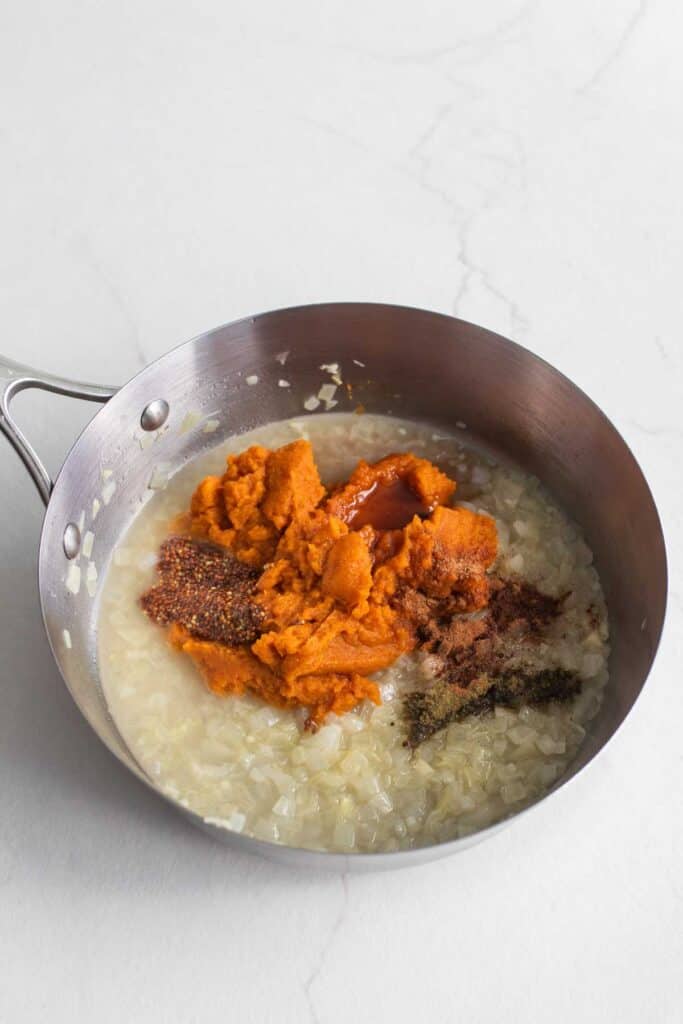 Pumpkin pasta sauce ingredients added to a stainless steel pan.