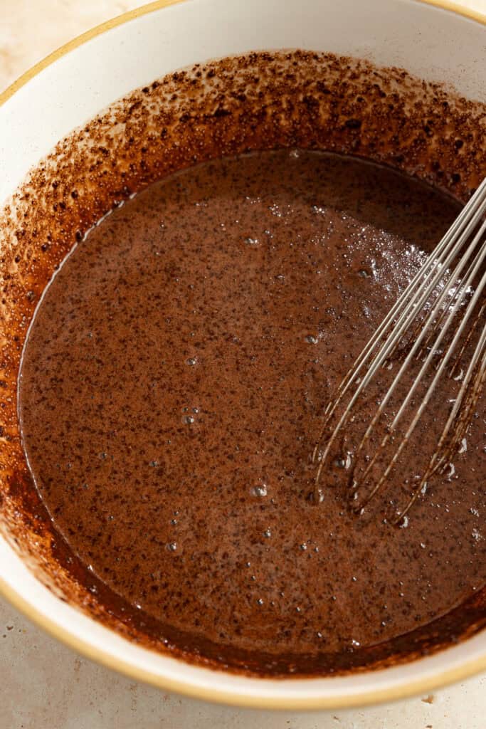 Wet ingredients mixed together for sourdough chocolate cake with a whisk sticking out of bowl.