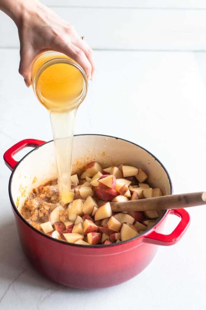 Broth in a mason jar poured into a dutch oven.