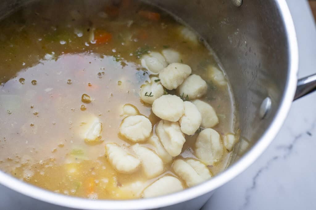 Gnocchi added to chicken soup in a large stock pot.