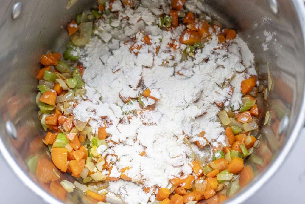 Flour sprinkled over cooked diced veggies in a large stock pot. 