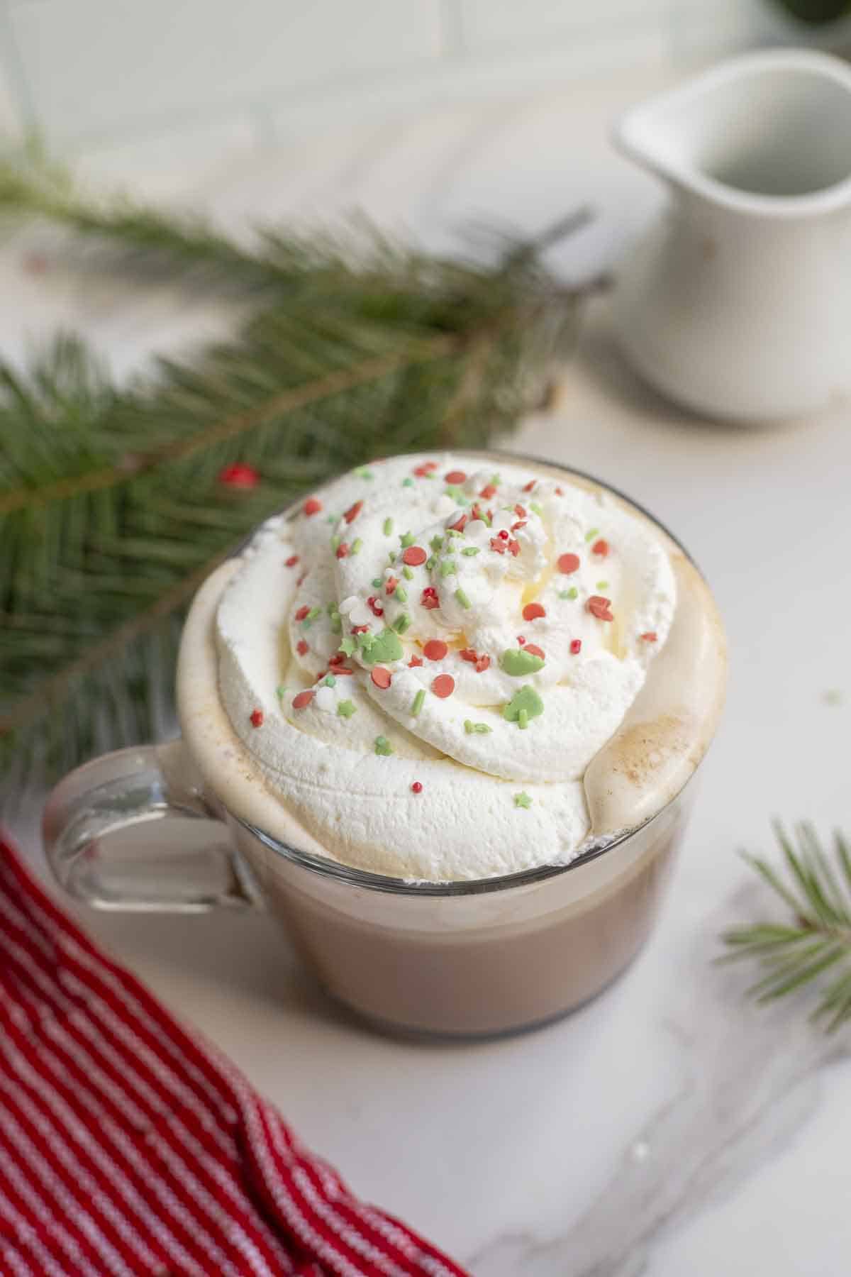 overhead photo of a peppermint mocha topped with whipped cream and sprinkles on a countertop with a red napkin.