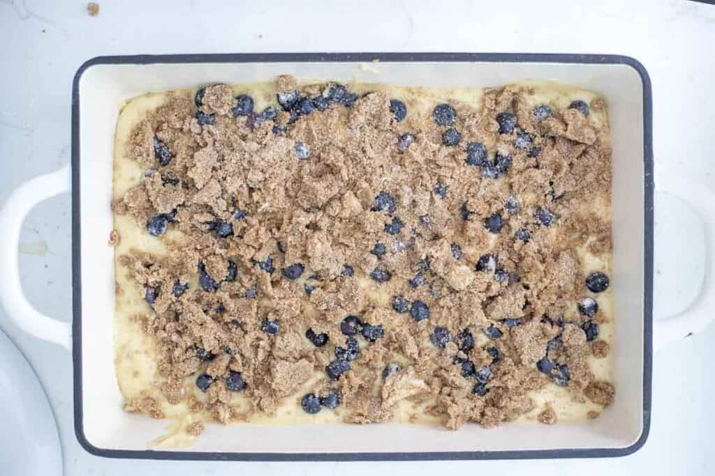 Sourdough coffee cake batter in a baking dish and topped with blueberries and crumble.