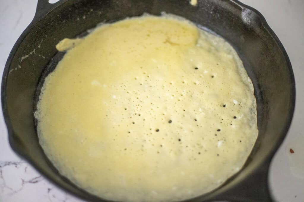 Crepe batter in a cast iron skillet.