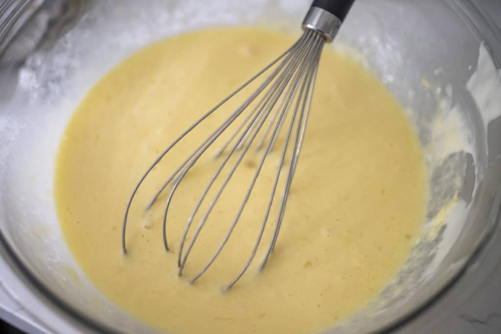 Sourdough crepes ingredients in a bowl with a whisk. 