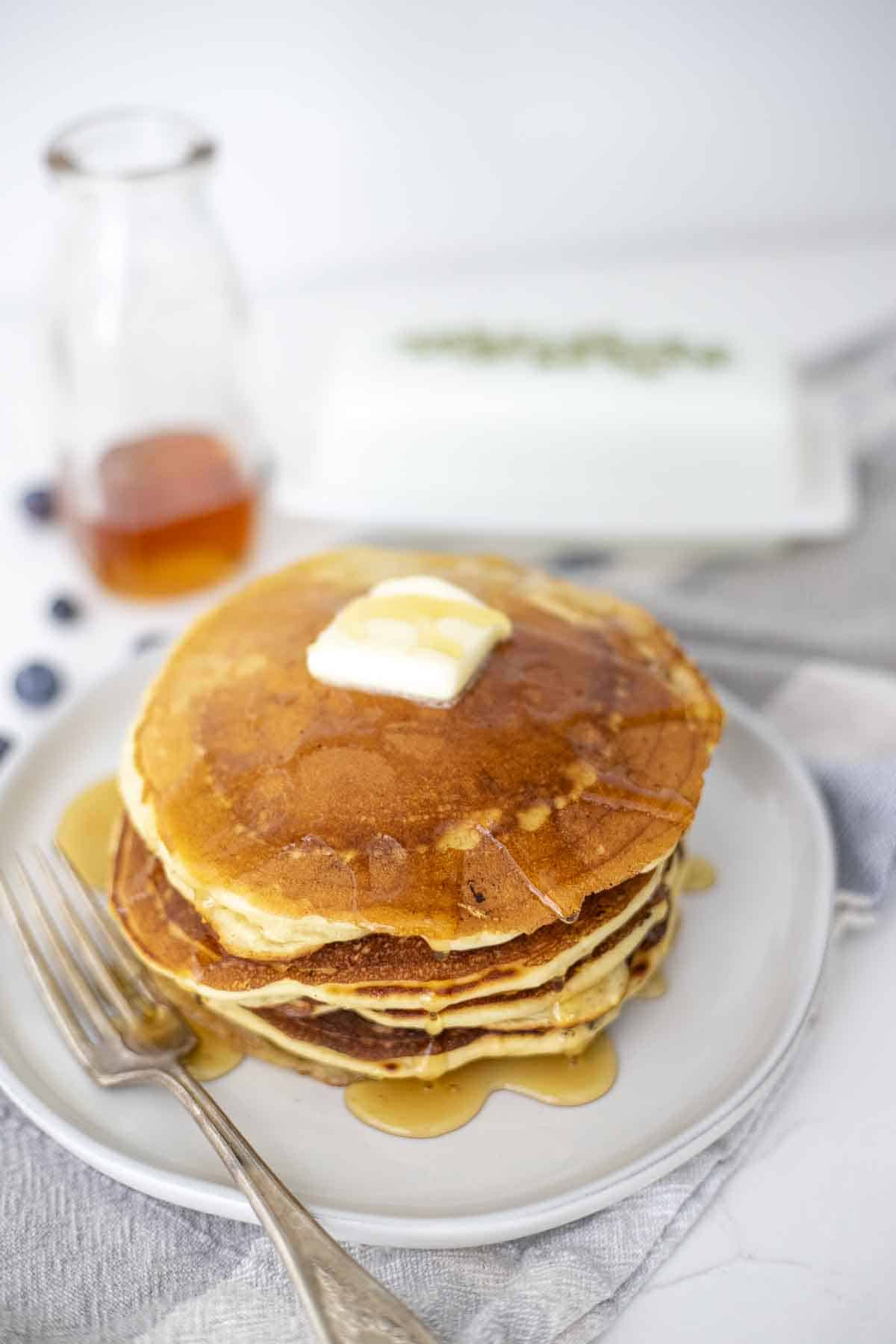 A stack of sourdough discard pancakes with a slab of butter on top. 